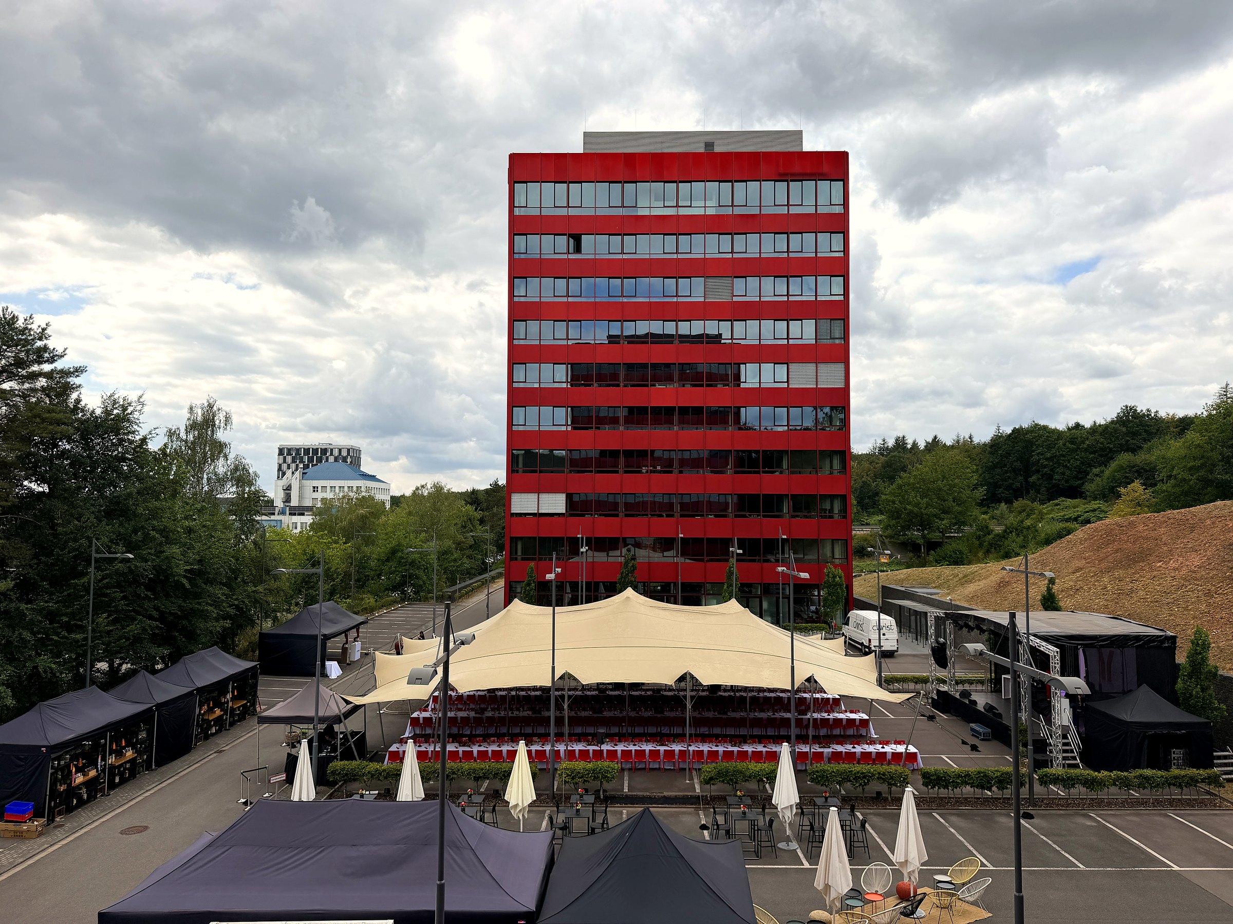Stretchzelt auf Firmenparkplatz mit langen Tafeln, Bühne und Catering-Pavillons bei einer Firmengala